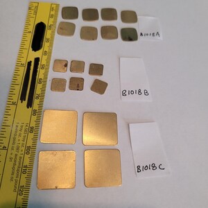 May include: A collection of 12 gold-colored metal squares of varying sizes. The squares are arranged in three rows, with the largest squares at the bottom. The squares are labeled with the letters "B1018A", "B1018B", and "B1018C".