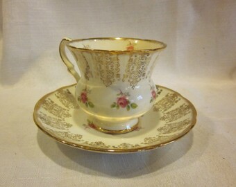 May include: A vintage teacup and saucer set with a delicate floral pattern and gold trim. The cup and saucer are white with a light pink floral design and gold accents.