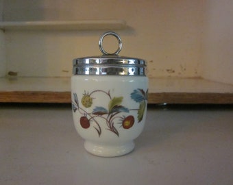 May include: White ceramic egg cup with a silver lid and a floral design featuring strawberries and leaves.