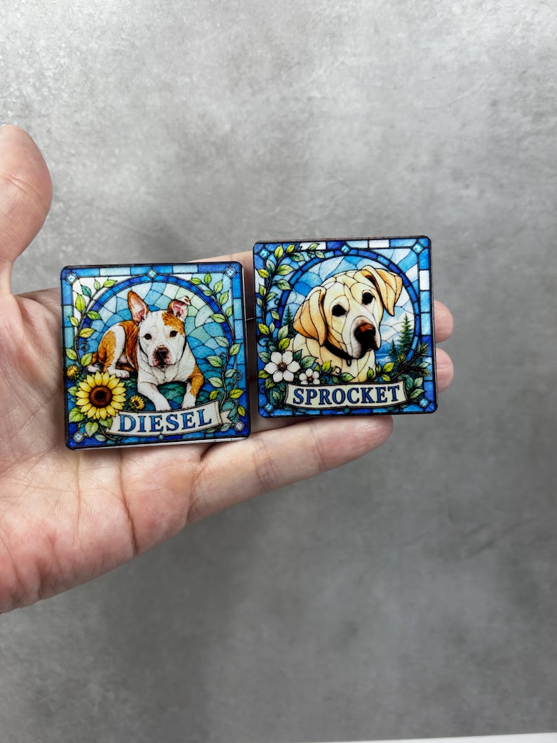 May include: Two square decorative tiles featuring stained glass style illustrations of dogs. One tile shows a white and brown dog with a sunflower and the name DIESEL. The other tile shows a yellow dog with white flowers and the name SPROCKET.