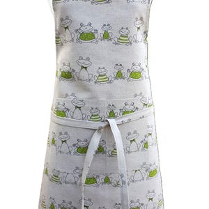 May include: A beige linen apron with a green frog pattern. The apron has two pockets and a tie at the waist.