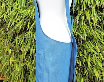 May include: A blue denim apron with a single pocket and adjustable straps. The apron is made of a durable, woven fabric.