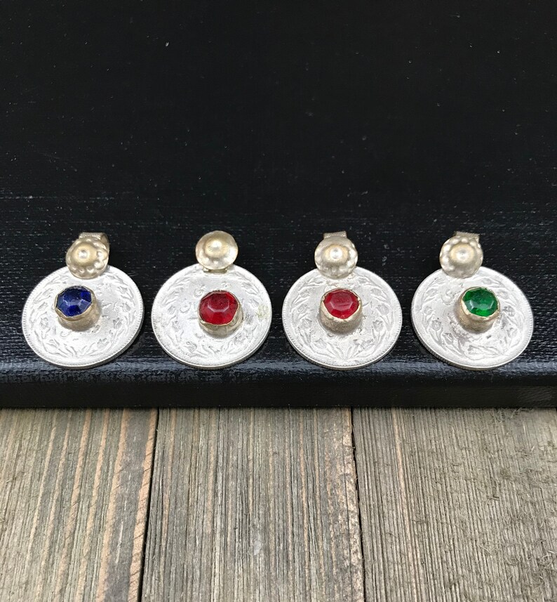 Puede incluir: Cuatro colgantes de plata con piedras de vidrio de diferentes colores. Los colgantes son redondos y tienen un dise&ntilde;o decorativo. Las piedras son azules, rojas, verdes y transparentes.
