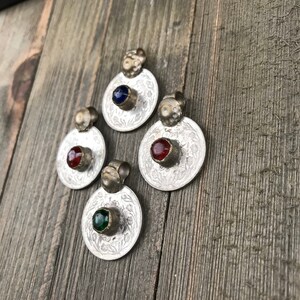 Puede incluir: Cuatro colgantes de plata con dise&ntilde;os ornamentados y piedras de vidrio de colores. Las piedras son azules, rojas, verdes y rojas.
