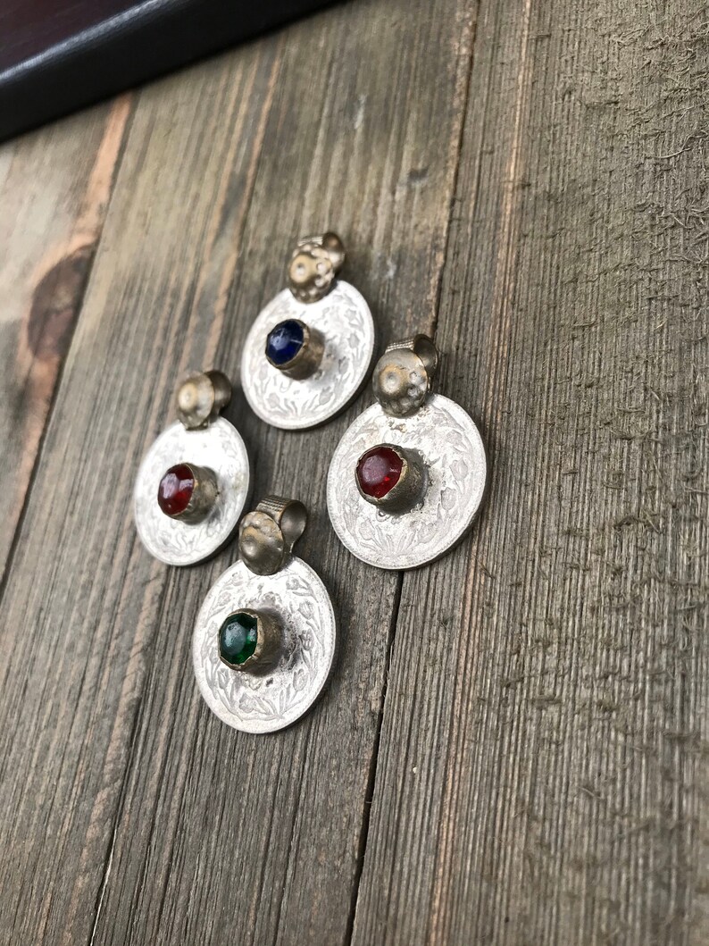 Puede incluir: Cuatro colgantes de plata con dise&ntilde;os ornamentados y piedras de vidrio de colores. Las piedras son azules, rojas, verdes y rojas.