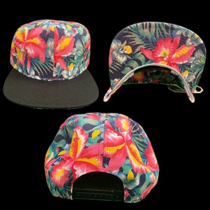 Puede incluir: Una gorra de b&eacute;isbol negra y azul con estampado floral tropical con flores rosas, amarillas y verdes. La gorra tiene una visera negra y una correa ajustable negra.
