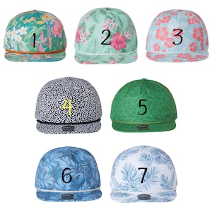 May include: Seven different patterned baseball caps with numbers 1 through 7 embroidered on the front. The caps are in various colors and patterns, including green, blue, pink, and white.