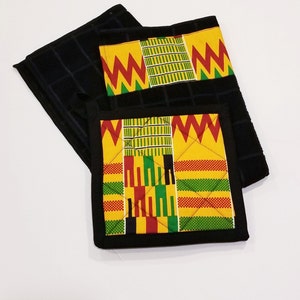May include: Set of two black kitchen towels with a yellow, red, green, and black patterned fabric insert. The insert features a geometric design.