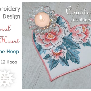 Könnte beinhalten: Ein doppelseitiger herzförmiger Untersetzer mit einem floralen Stickmuster. Der Untersetzer ist rosa und weiß mit einem blaugrünen Blumenmuster. Der Text "Coaster double-sided" ist auf dem Bild gedruckt. Der Text "Iva Art Stitch" ist ebenfalls auf dem Bild gedruckt.