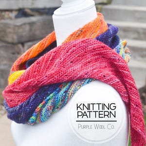May include: A colorful knitted scarf in shades of orange, red, blue, and green. The scarf is draped around a white mannequin. The text "Knitting Pattern Purple Wool Co." is printed on a white circle.