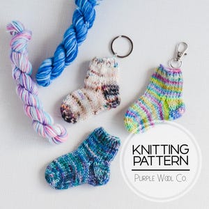 Op de afbeelding: Een verzameling miniatuur gebreide sokken in verschillende kleuren, sommige met sleutelhangers. Er zijn ook twee strengen kleurrijk garen. De afbeelding bevat de tekst "KNITTING PATTERN" en "Purple Wool Co."