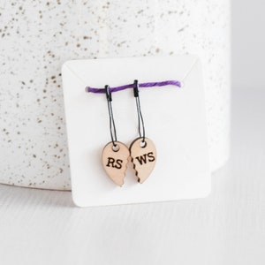 May include: Two wooden heart-shaped stitch markers with black thread loops. The hearts are broken in half and each half is labeled "RS" and "WS".