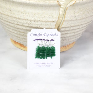 May include: Set of four green stitch markers with silver rings. The markers are shaped like the word "Knit" and are packaged on a white card with the text "Camelot Dyeworks" and "camelotdyeworks.com Made in Michigan".