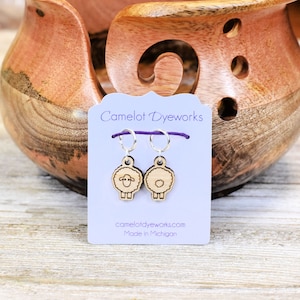 May include: A pair of wooden sheep stitch markers with silver rings and purple yarn. The card reads "Camelot Dyeworks" and "camelotdyeworks.com Made in Michigan".