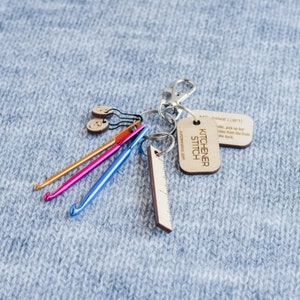 May include: A keychain with a wooden tag that says "KITCHENER STITCH" and "purplerwooluo.com". The keychain also has a wooden ruler, three crochet hooks, and two wooden buttons.