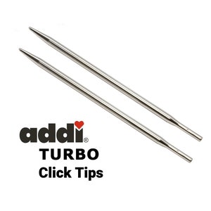 May include: A pair of silver Addi Turbo Click interchangeable knitting needles. The needles are made of metal and have a smooth, shiny finish. The needles are designed to be used with the Addi Turbo Click system, which allows you to easily change the needle size.