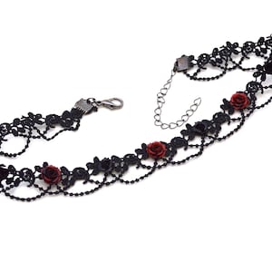 Può includere: Un girocollo in pizzo nero con una catena argentata e dettagli di rose rosse.