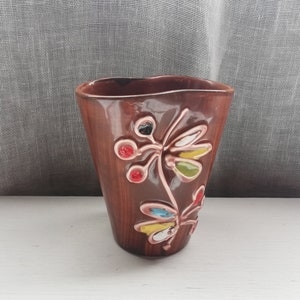 May include: A brown ceramic vase with a wavy rim and a floral design. The vase is decorated with colorful flowers and leaves.