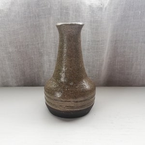 以下が含まれることがあります： 茶色の斑点のある釉薬が施された、濃い茶色の縁のある小さな陶器の花瓶