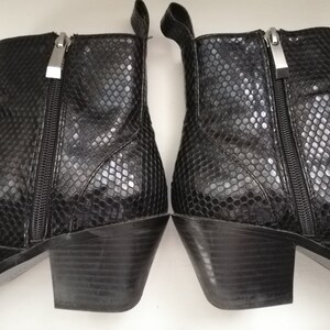 Może przedstawiać: Para czarnych botk&oacute;w z blokowym obcasem i wzorem sk&oacute;ry węża. Botki mają zamek błyskawiczny po wewnętrznej stronie każdego buta.