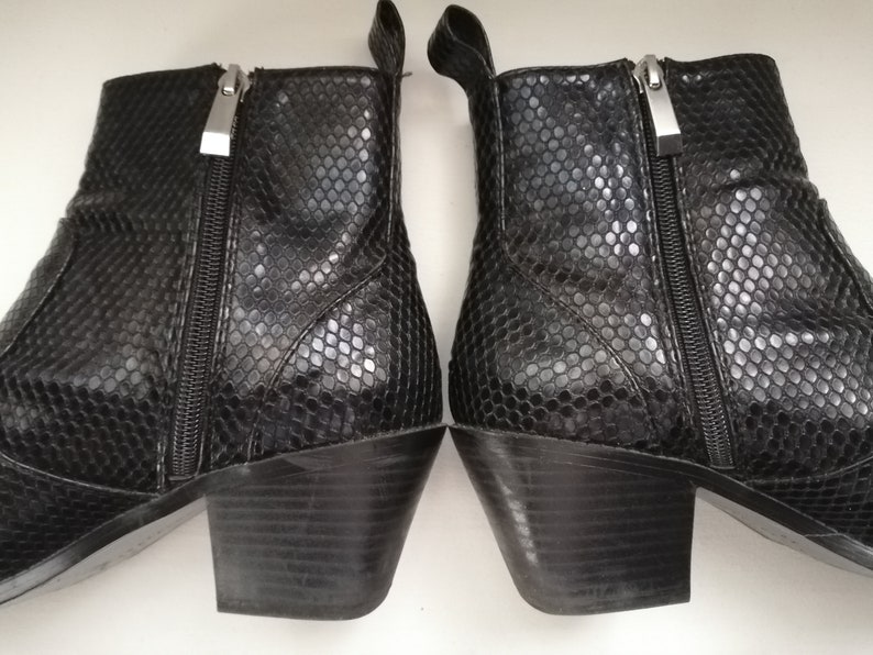 Może przedstawiać: Para czarnych botk&oacute;w z blokowym obcasem i wzorem sk&oacute;ry węża. Botki mają zamek błyskawiczny po wewnętrznej stronie każdego buta.