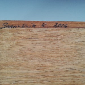 May include: Close-up of a wooden surface with the inscription "Sven-Erik K. 2002" in black ink.