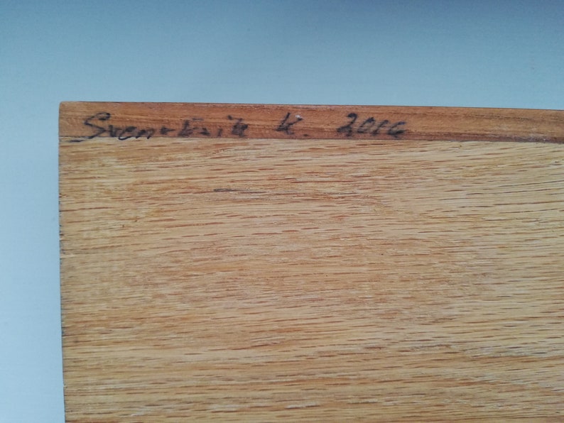 May include: Close-up of a wooden surface with the inscription "Sven-Erik K. 2002" in black ink.
