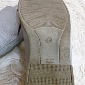 May include: Close-up of the sole of a gray leather shoe with a brown rubber outsole. The shoe size is 45 and the text "Finnish Design" is printed on the sole.