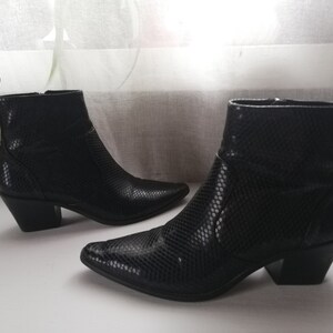 Może przedstawiać: Para czarnych kowbojskich but&oacute;w ze sk&oacute;ry węża z ostrymi noskami i blokowym obcasem.