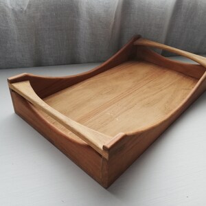 May include: A wooden serving tray with two handles. The tray is made of light brown wood and has a natural finish.