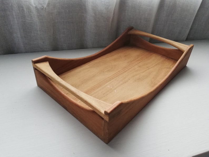 May include: A wooden serving tray with two handles. The tray is made of light brown wood and has a natural finish.