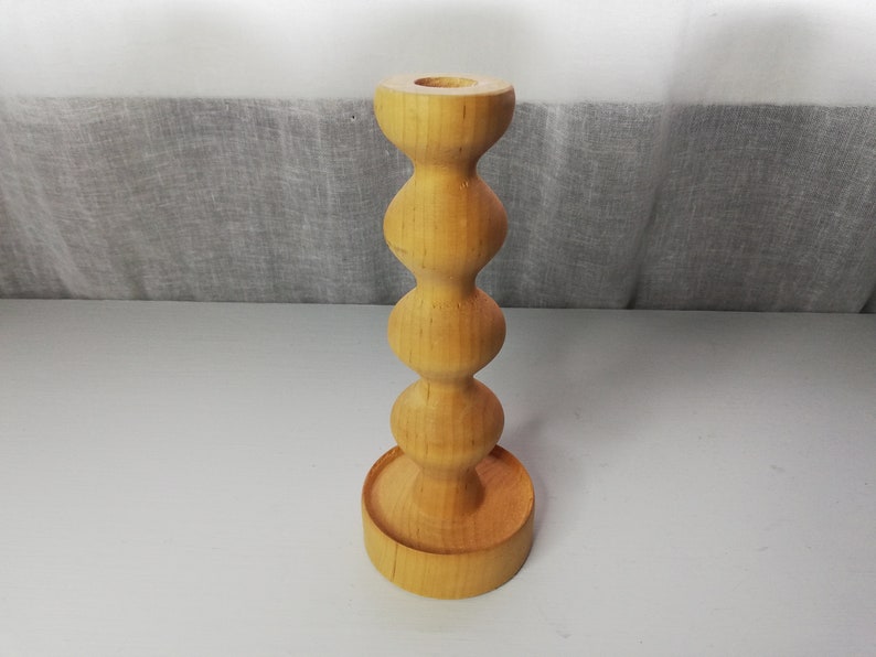 Puede incluir: Un portavelas de madera con un dise&ntilde;o redondeado y bulboso. El portavelas est&aacute; hecho de madera marr&oacute;n claro y tiene un acabado liso.