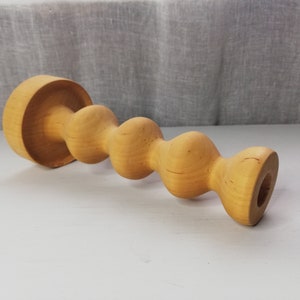 Puede incluir: Un portavelas de madera con un dise&ntilde;o &uacute;nico y retorcido. El portavelas est&aacute; hecho de madera marr&oacute;n claro y tiene un acabado liso y pulido.