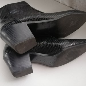 Może przedstawiać: Para czarnych botk&oacute;w z imitacji sk&oacute;ry węża, z ostrym noskiem i grubym obcasem.