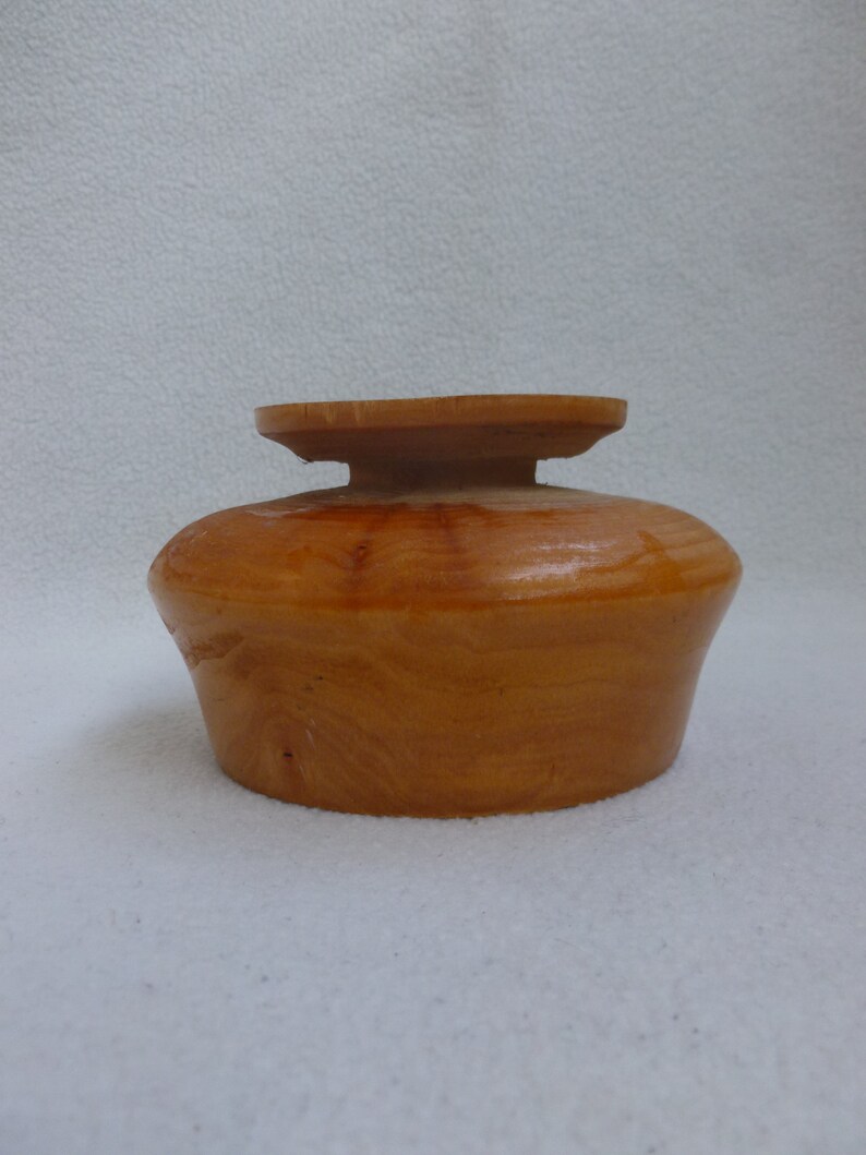 May include: A wooden bowl with a natural wood finish. The bowl has a rounded shape and a slightly raised rim.