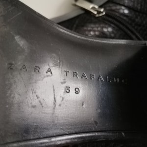Może przedstawiać: Zbliżenie na podeszwę czarnego sk&oacute;rzanego buta z wytłoczonym tekstem "ZARA TRAFALUC 39" na spodzie.