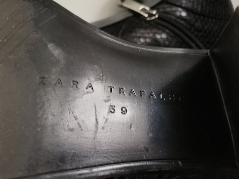 Może przedstawiać: Zbliżenie na podeszwę czarnego sk&oacute;rzanego buta z wytłoczonym tekstem "ZARA TRAFALUC 39" na spodzie.