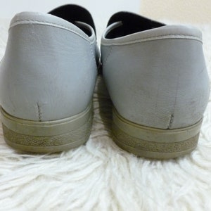 May include: A pair of gray leather slip-on shoes with a brown rubber sole.