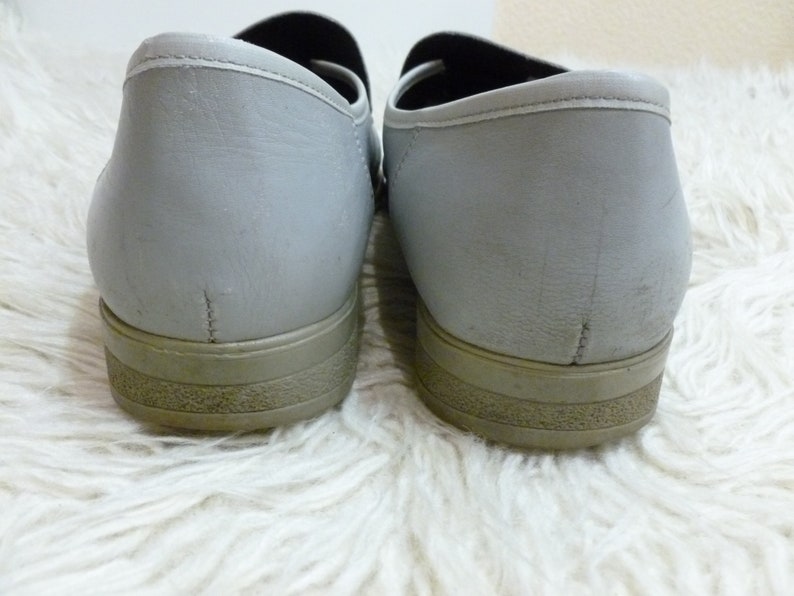 May include: A pair of gray leather slip-on shoes with a brown rubber sole.