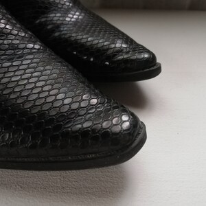 Może przedstawiać: Para czarnych sk&oacute;rzanych but&oacute;w ze wzorem sk&oacute;ry węża.