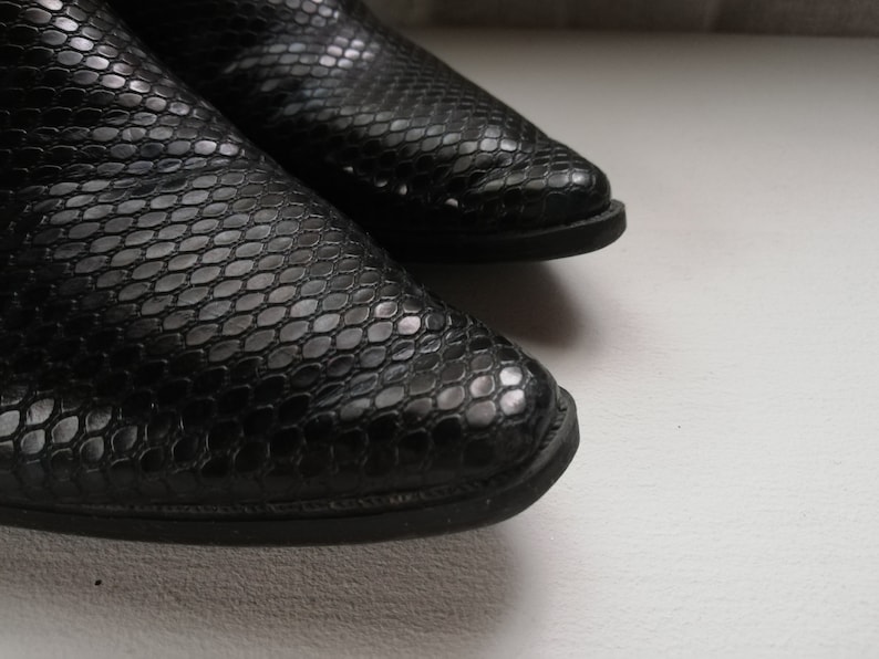 Może przedstawiać: Para czarnych sk&oacute;rzanych but&oacute;w ze wzorem sk&oacute;ry węża.