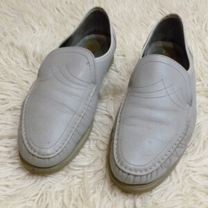 May include: A pair of gray leather slip-on shoes with a decorative stitching detail on the toe.