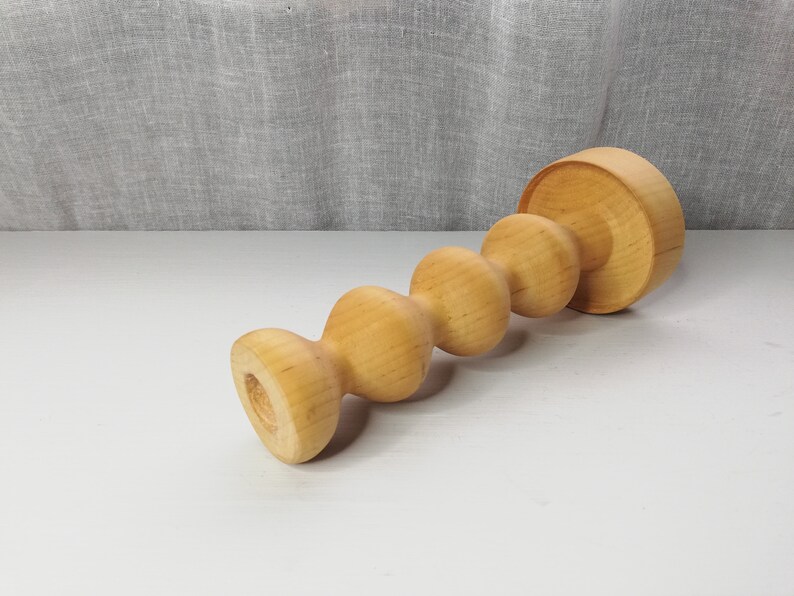 Puede incluir: Un portavelas de madera con un dise&ntilde;o &uacute;nico y retorcido. El portavelas est&aacute; hecho de madera marr&oacute;n claro y tiene un acabado liso y pulido.