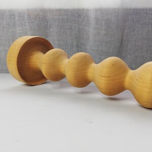 Puede incluir: Un portavelas de madera con un dise&ntilde;o &uacute;nico y retorcido. El portavelas est&aacute; hecho de madera natural y tiene un color marr&oacute;n claro.