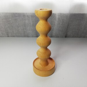 Puede incluir: Un portavelas de madera con un dise&ntilde;o redondeado y bulboso. El portavelas est&aacute; hecho de madera marr&oacute;n claro y tiene un acabado liso.
