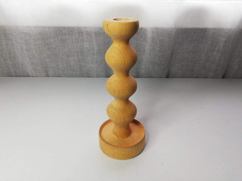 Puede incluir: Un portavelas de madera con un dise&ntilde;o redondeado y bulboso. El portavelas est&aacute; hecho de madera marr&oacute;n claro y tiene un acabado liso.