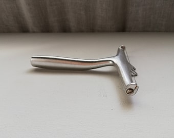 May include: A silver cheese slicer with a wire loop and a handle. The slicer is designed to cut thin slices of cheese.