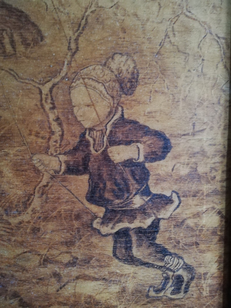 May include: A woodburned image of a person wearing a hat and coat, holding a rope, with a tree in the background.