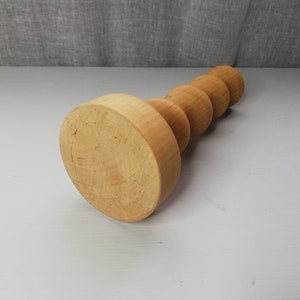Puede incluir: Un portavelas de madera con una base redonda y una serie de pomos redondos apilados.
