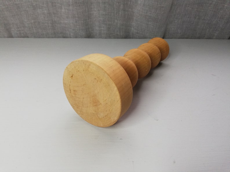 Puede incluir: Un portavelas de madera con una base redonda y una serie de pomos redondos apilados.